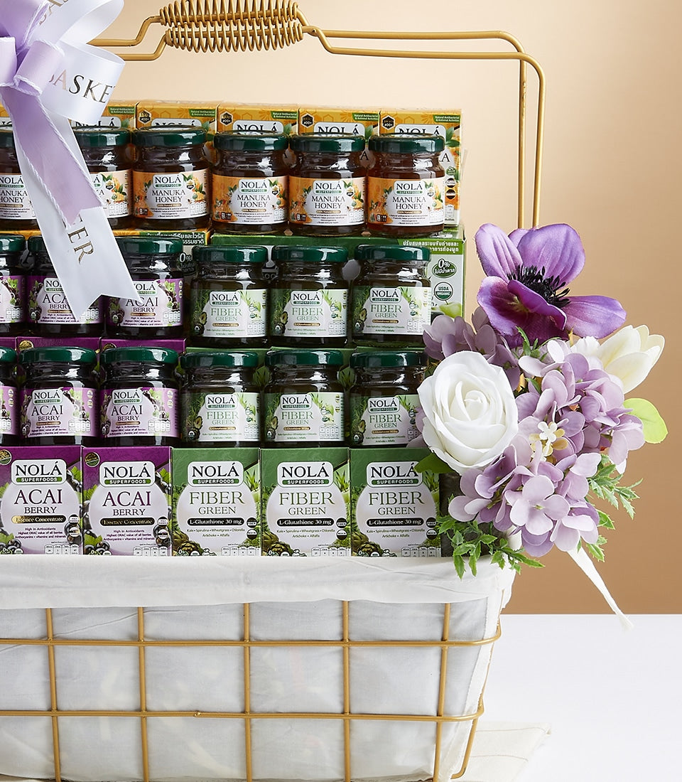 Large white and gold gift basket filled with NOLA Superfoods wellness products including manuka honey, acai berry, and fiber