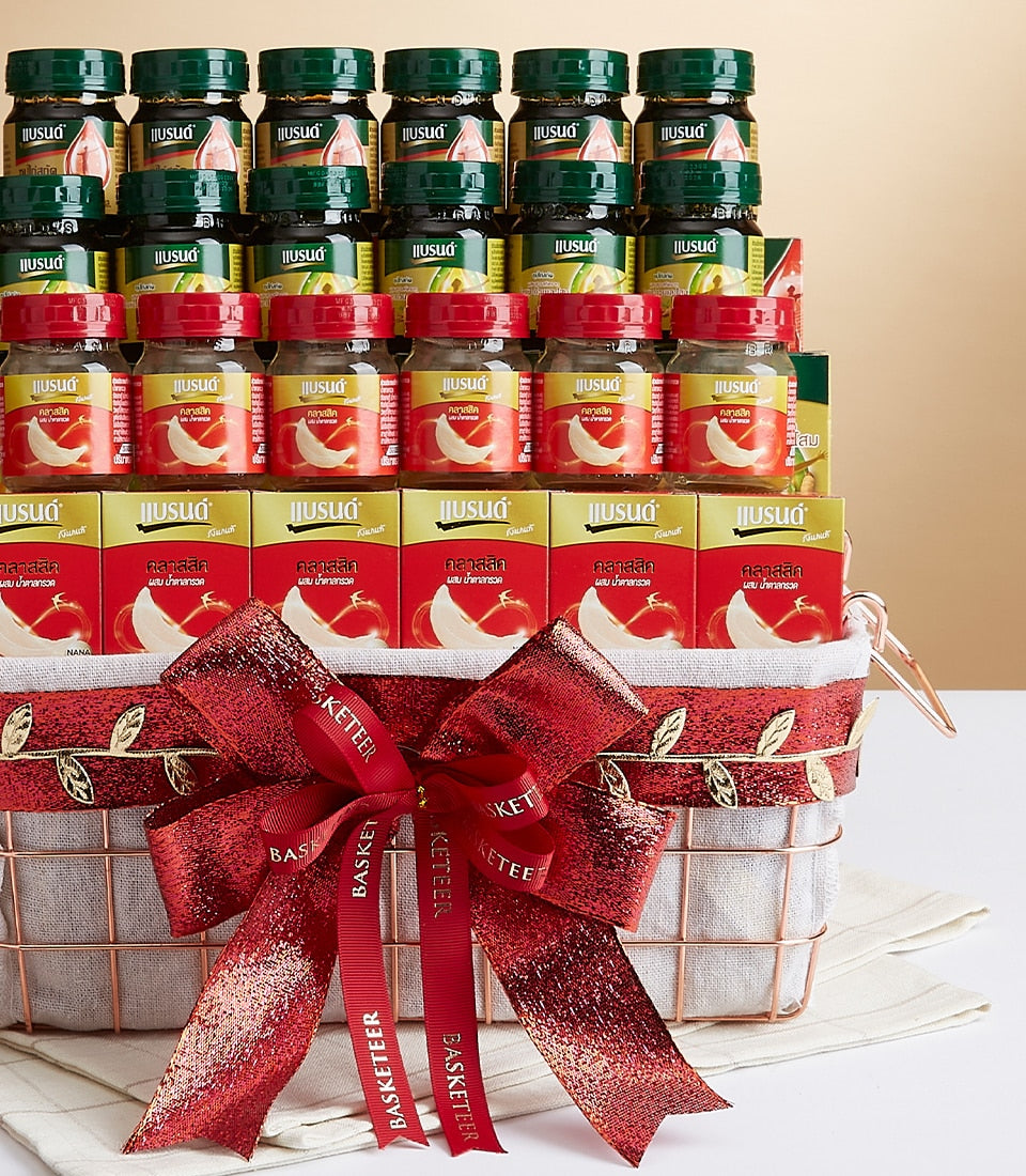 Premium wellness gift basket with bottled health drinks and gourmet boxes in rose gold wire basket, topped with red bow