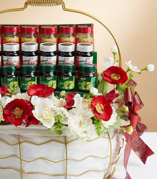 Luxury mixed wellness gift basket with bottled health essentials, red poppies, white orchids, and gold-trimmed white fabric