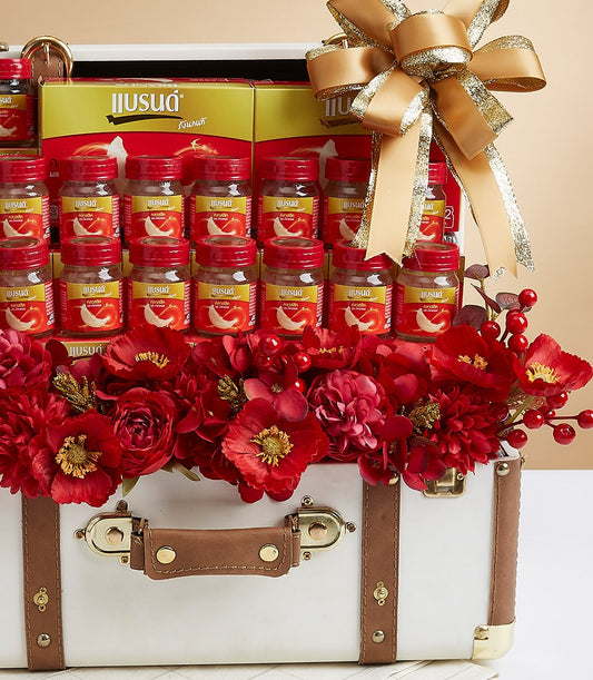 Premium bird's nest gift hamper in elegant suitcase box with red glass jars, gold ribbon, and luxury floral arrangement