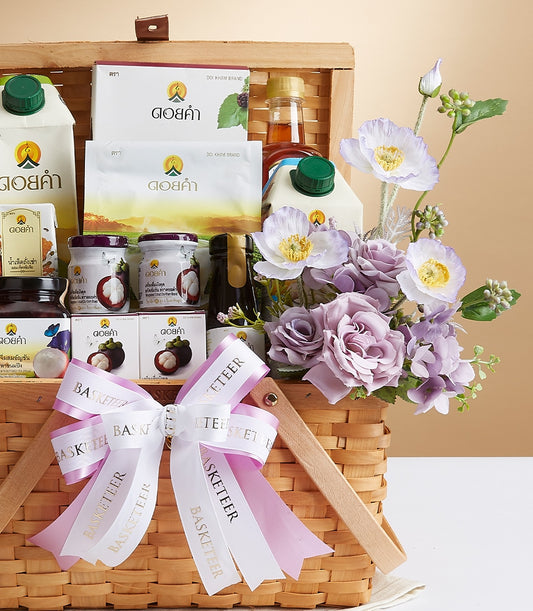 Prestige Doi Kham wicker gift basket with wellness foods, juices, and mangosteen jars, topped with white and pink bow