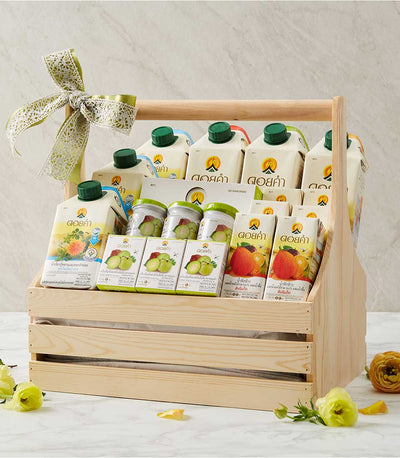 Wooden crate gift basket with Doi Kham wellness drinks, green guava preserves, and fresh juices tied with green and white