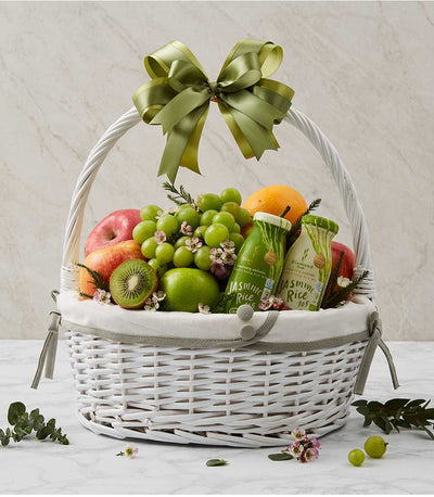 Handcrafted white wicker wellness fruit basket with fresh apples, grapes, kiwi, orange, botanical touches and wellness