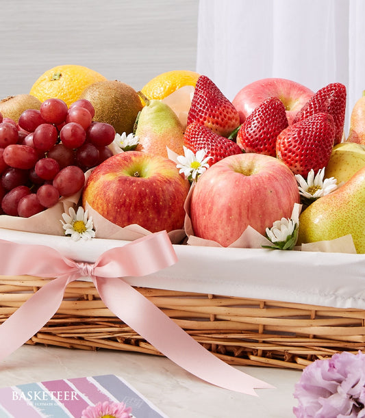 Luxe wicker fruit basket with fresh grapes, apples, kiwis, and strawberries, tied with pink satin ribbon