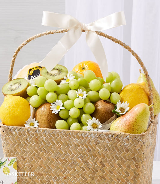 Premium woven fruit basket with fresh grapes, kiwis, lemons, pears, and orange, cream satin bow