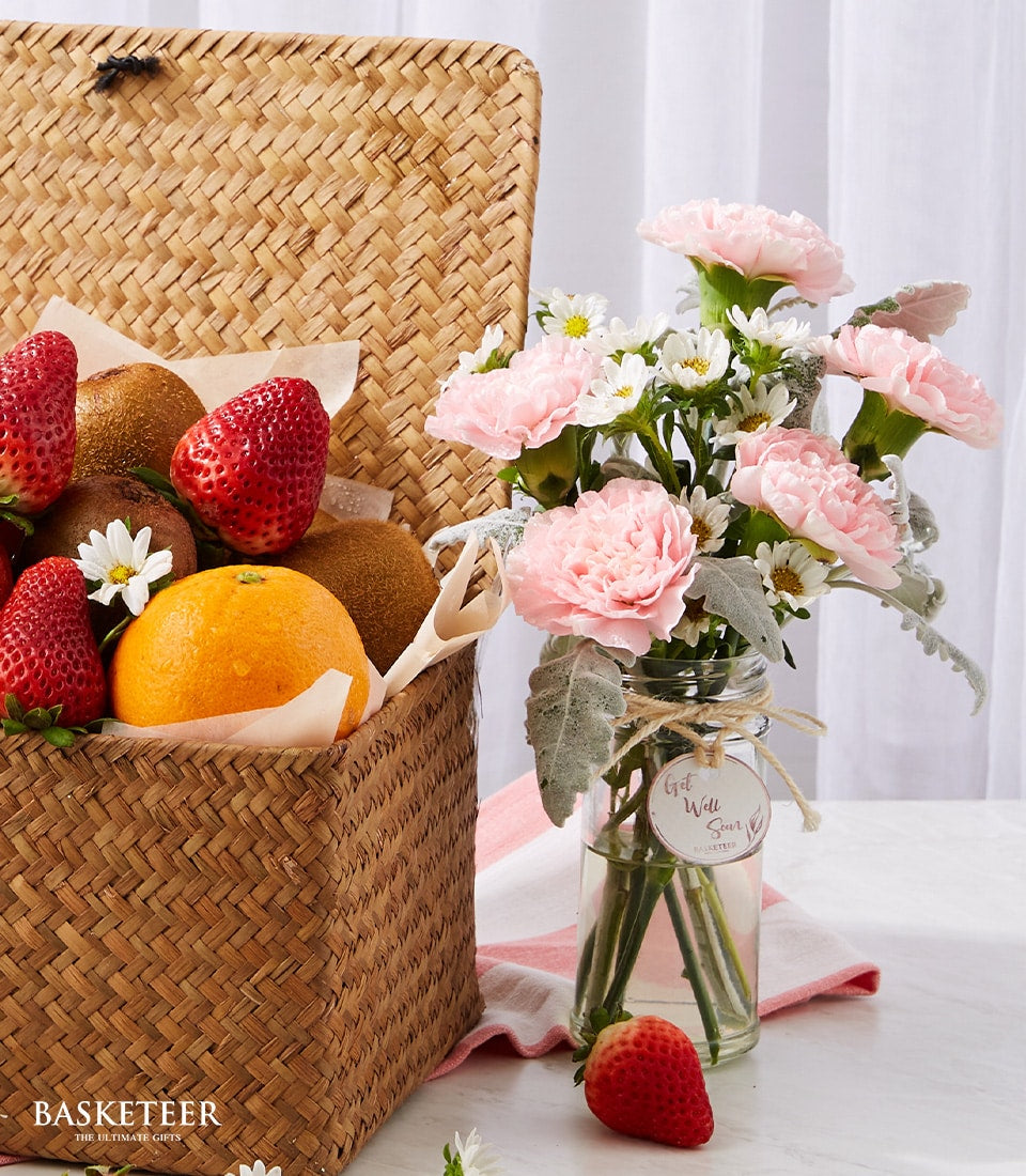 Fresh fruit wellness basket with strawberries, kiwis, oranges and pink carnation flowers for get well recovery