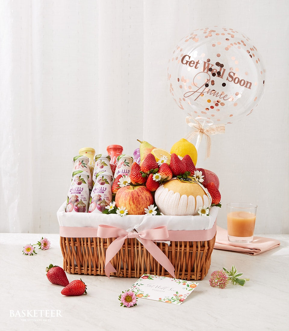 Fresh fruit and juice gift basket with pink ribbon bow and get well soon balloon for recovery care