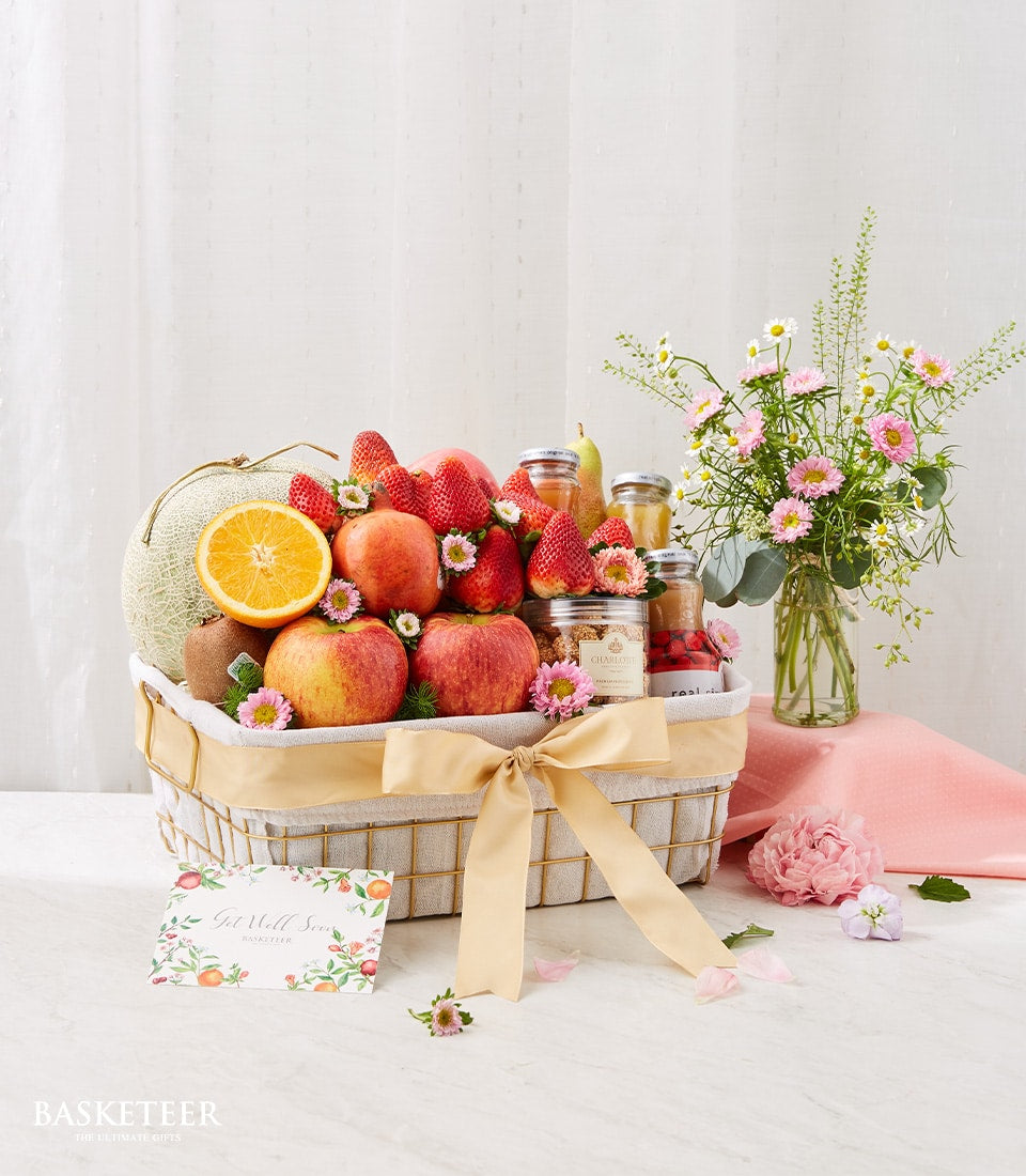 Fresh fruit and gourmet get well gift basket with strawberries, apples, preserves, paired with pink daisies