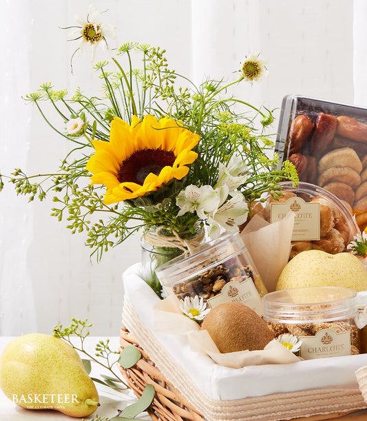 Wicker gift basket with yellow sunflower arrangement, fresh fruits, nuts, and gourmet treats for get well recovery