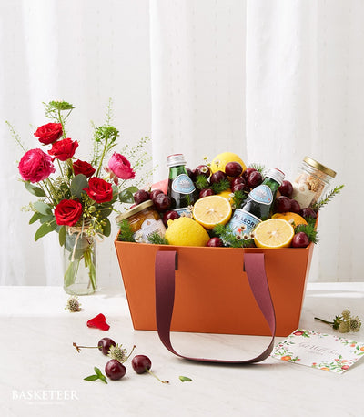 Premium wellness fruit basket with fresh lemons, cherries, sparkling water, and gourmet spreads, paired with red roses and