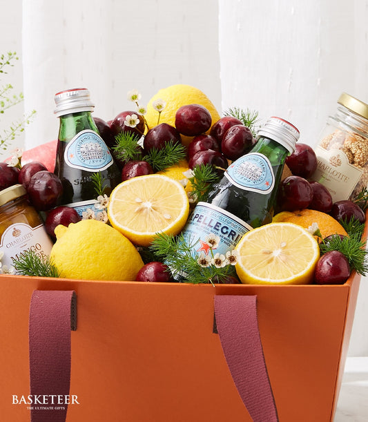 Premium wellness fruit basket with lemons, cherries, oranges, sparkling water, and mango preserve in woven container