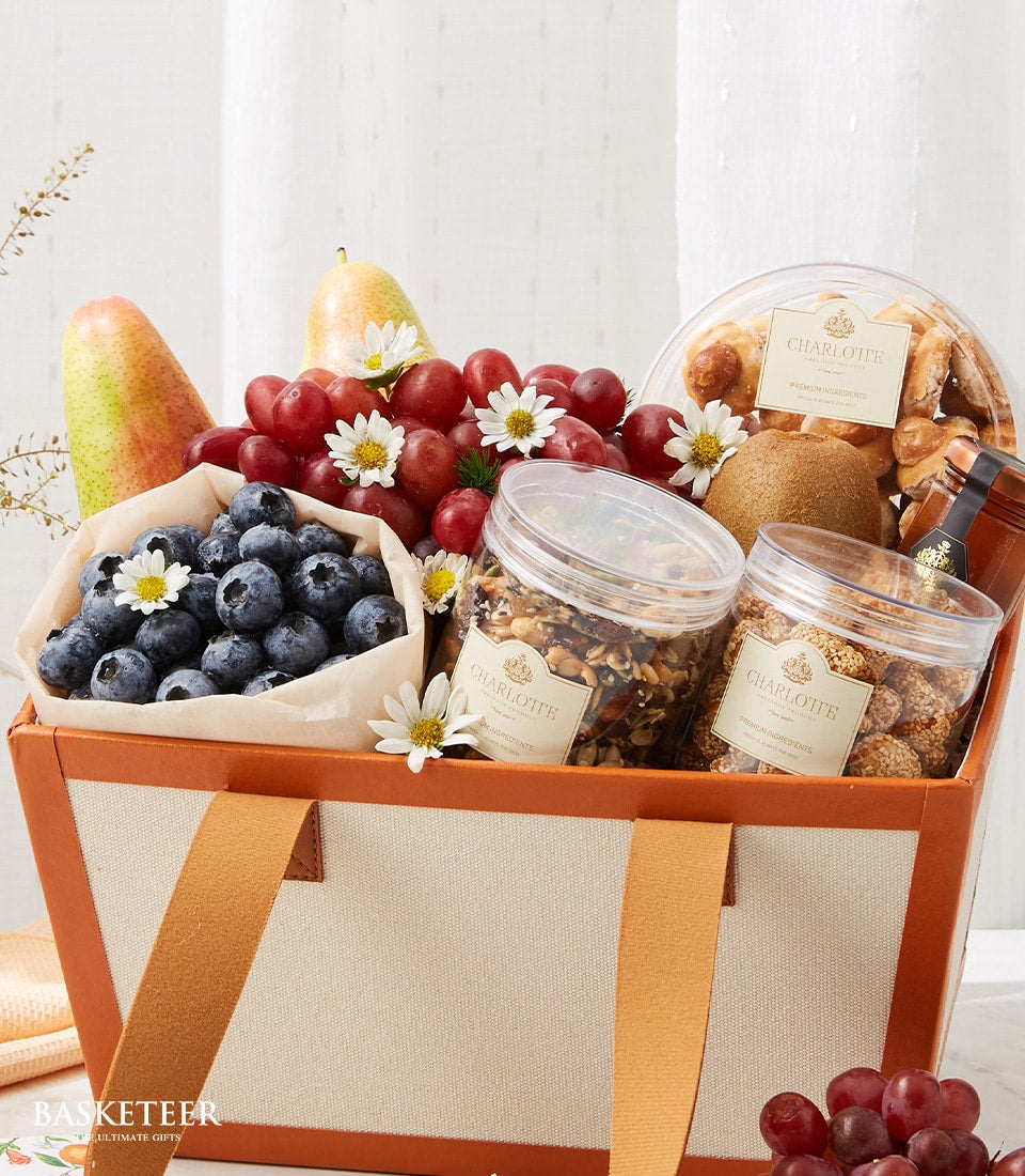 Premium fresh fruit, gourmet treats and white daisies in cream canvas recovery gift basket