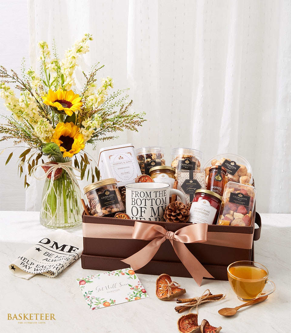 Recovery gift basket with Darjeeling tea, gourmet nuts, and fresh yellow sunflowers in glass vase