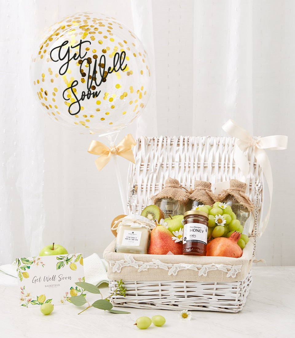 White wicker get well basket with fresh fruit, honey, and coconut cream, gold confetti balloon