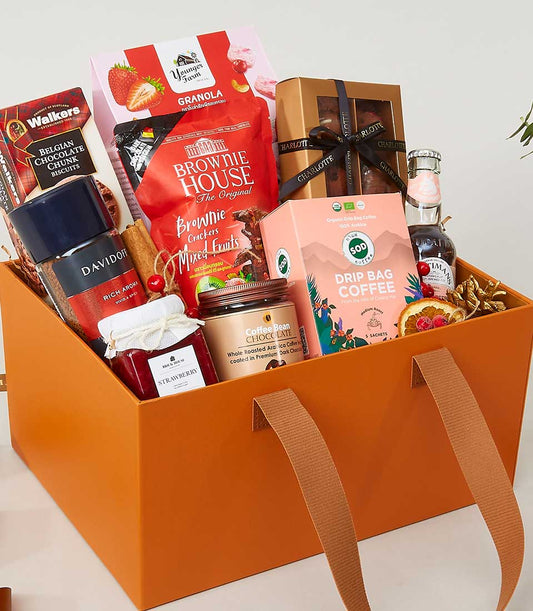 Premium gourmet gift hamper in orange leather carryall with granola, brownies, coffee, and jam for New Year gifting
