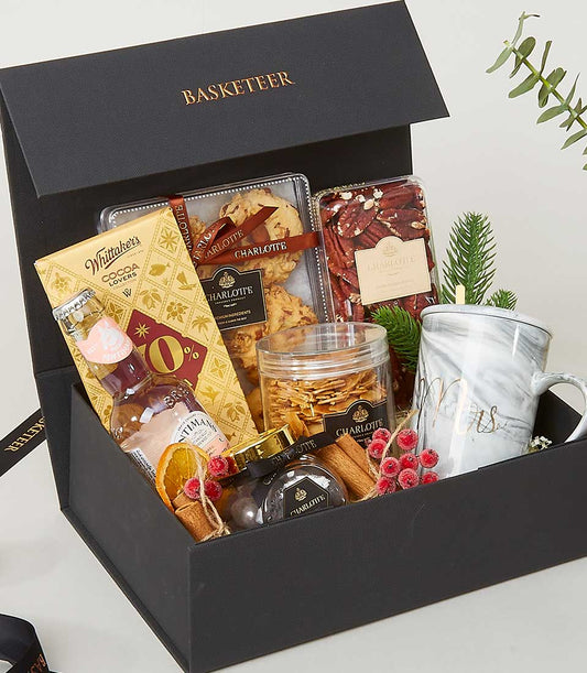 Luxury New Year gift box with gourmet treats, glass mug, and festive decorations
