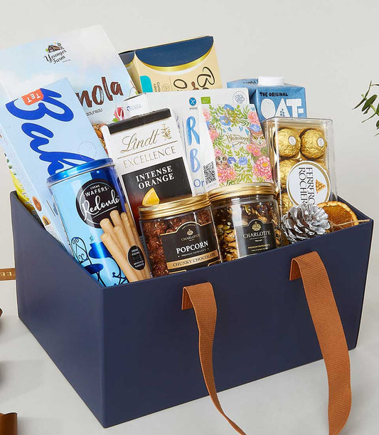 Luxury navy leather-handle gift box with gourmet chocolates, granola, wafers, and artisan snacks for New Year gifting
