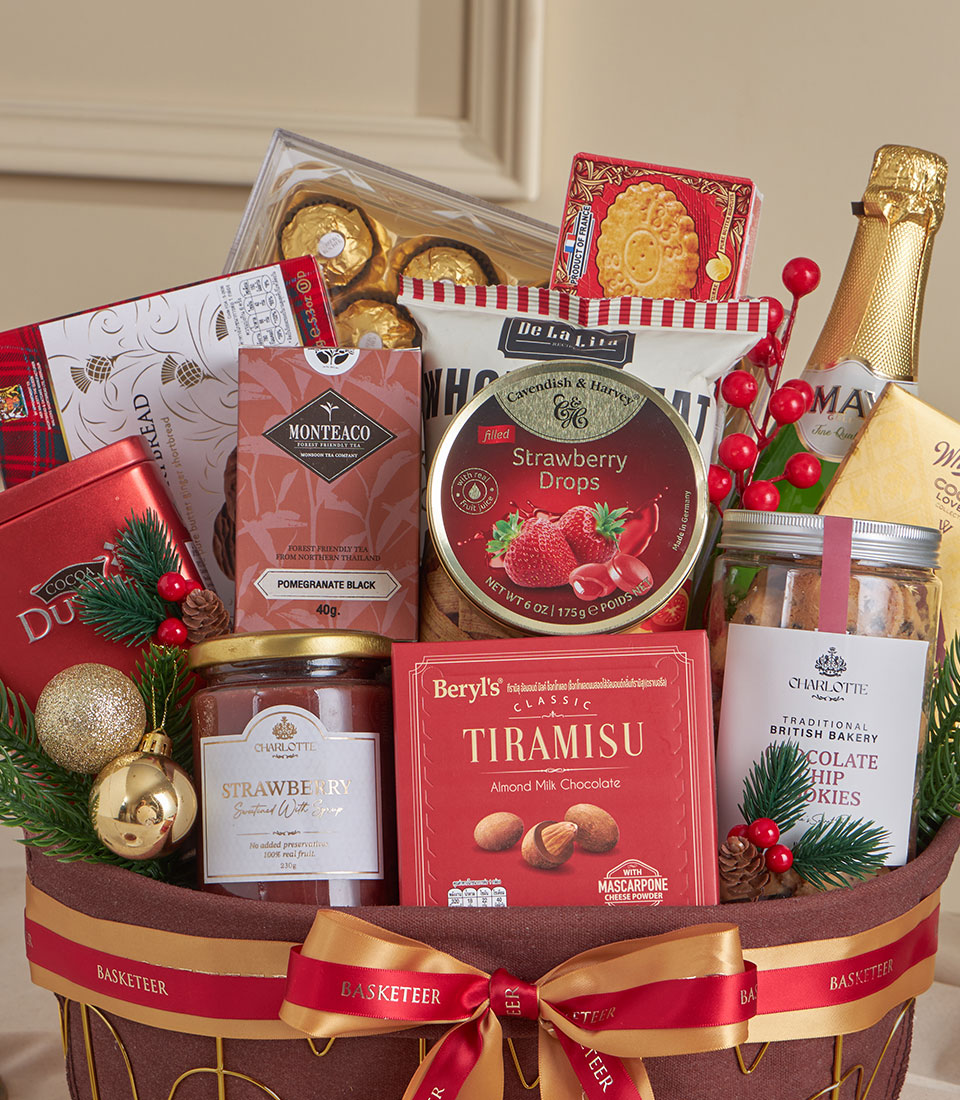 Dark wicker gift basket with red and gold ribbon filled with champagne, tiramisu chocolate, premium tea, cookies, and