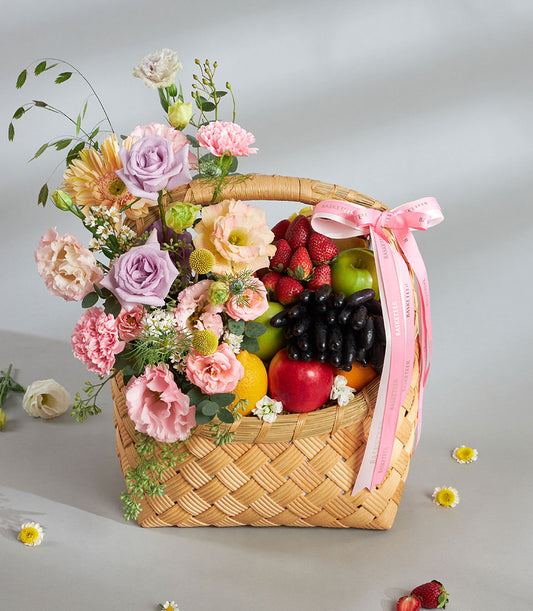 Premium fruit basket with pastel pink and purple florals, fresh apples, citrus and berries for birthday gifting