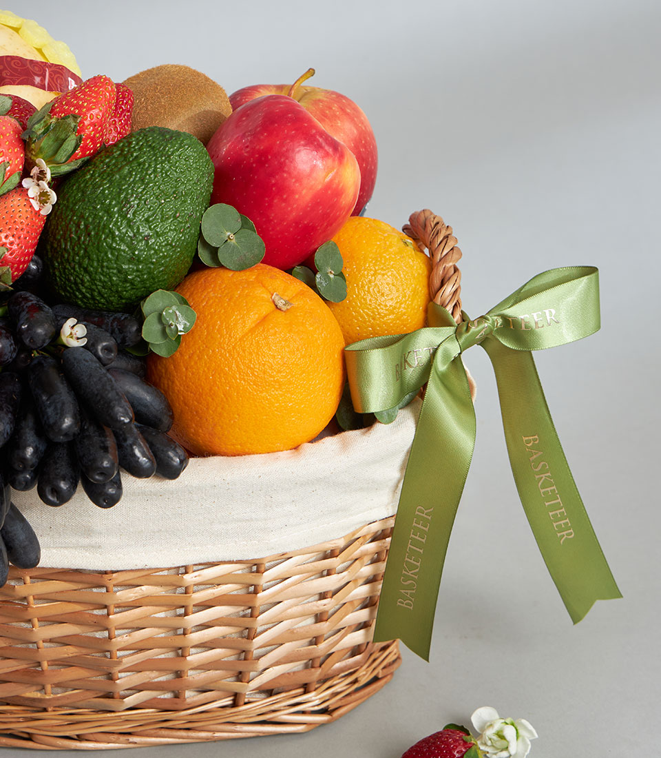 Premium wicker fruit basket with moon drop grapes, strawberries, oranges, kiwis, avocados and apples, light green ribbon bow