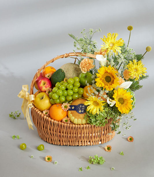 Bright yellow fruit and floral gift basket with fresh apples, grapes, citrus, sunflowers and gerbera daisies in woven wicker