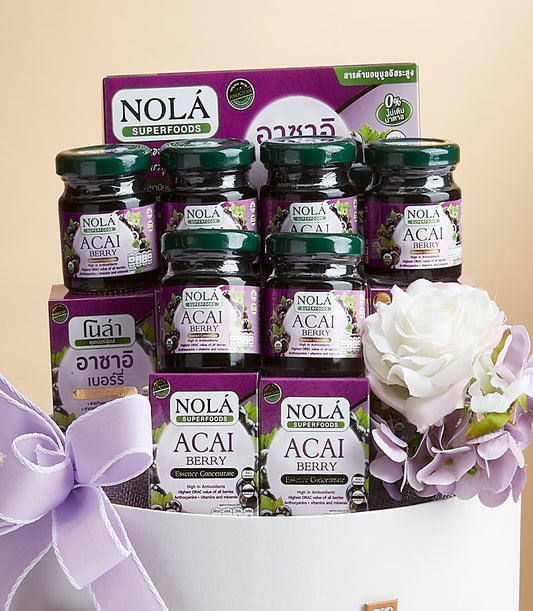 Nola Acai Berry superfood gift set with glass jars, essence concentrate boxes, and purple ribbon in white basket