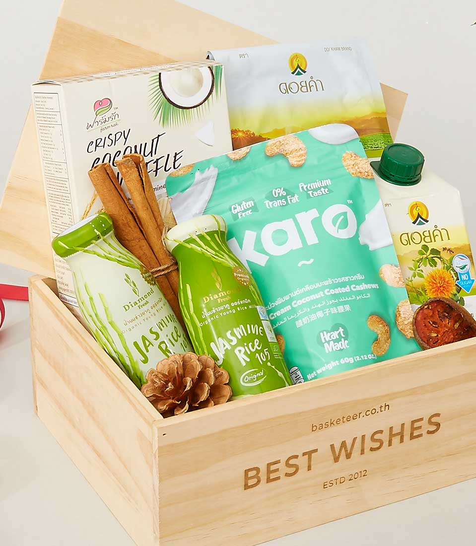 Wooden gift box with gourmet treats including crispy coconut waffle, cashews, and jasmine rice drink for New Year gifting