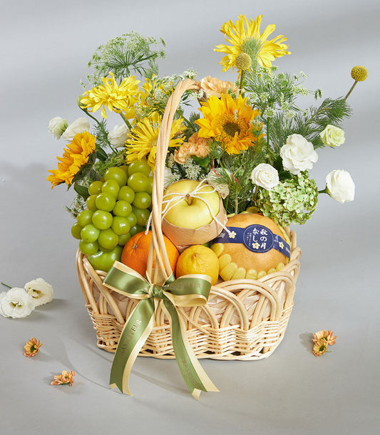 Bright yellow fruit and floral gift basket with sunflowers, roses, fresh citrus, and grapes in woven wicker