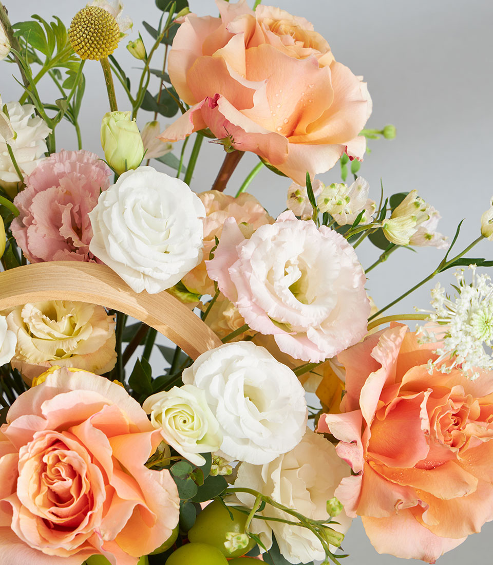 Premium peach and blush pastel floral basket with fresh roses, lisianthus, and garden fruits for birthday celebrations