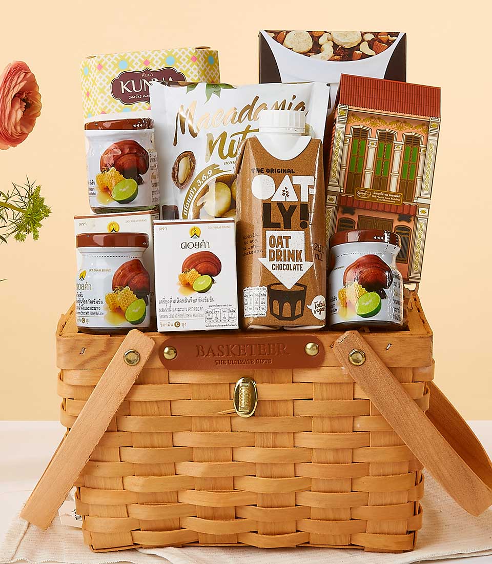 Luxury health and wellness gift basket with macadamia nuts, oat drink, and gourmet preserves in woven wood carrier