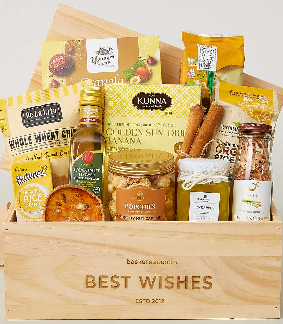 Light wood crate filled with wellness snacks, organic granola, dried fruit, and herbal infusions for New Year gifting