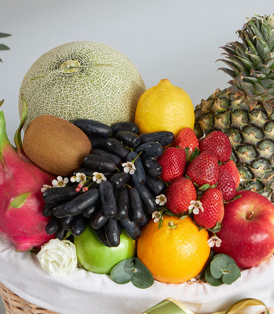 Premium tropical and imported fruit basket with cantaloupe, pineapple, dragon fruit, grapes, and fresh citrus in woven basket