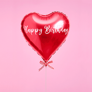 Red heart-shaped Happy Birthday foil balloon with white script and polka-dot ribbon