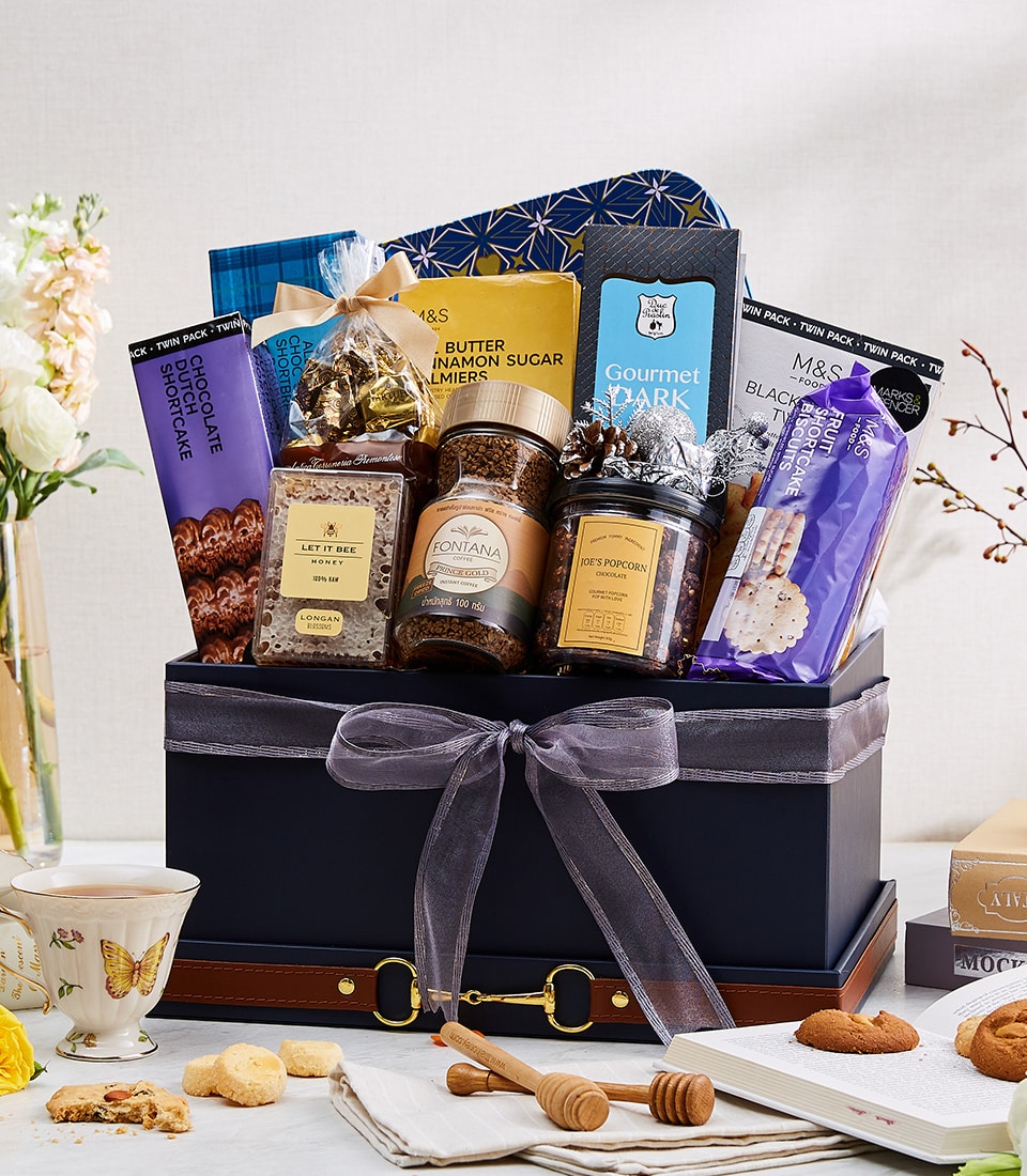 Luxurious dark blue gourmet gift hamper with chocolate, coffee, honey, and biscuits, tied with grey ribbon and gold hardware