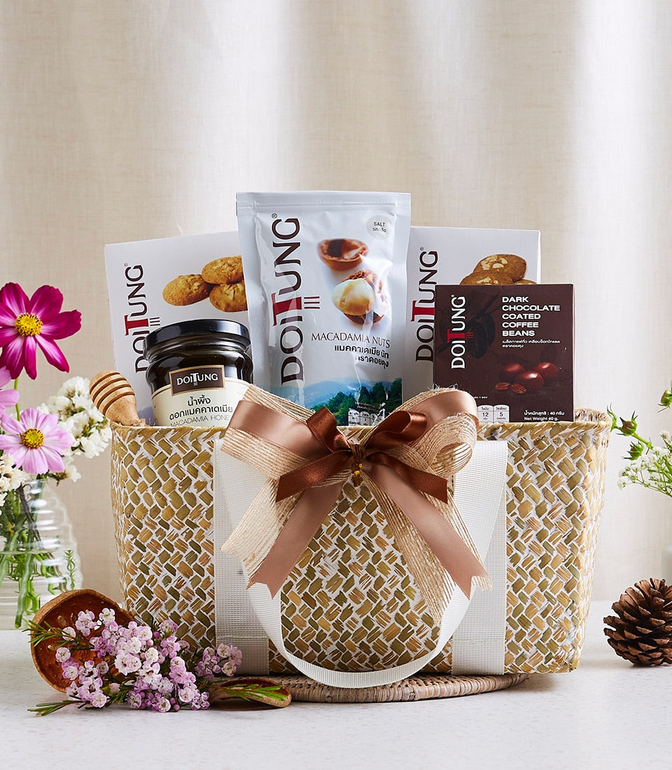 Woven straw gift basket with macadamia nuts, dark chocolate coffee beans, macadamia honey, gold and brown ribbon bow,
