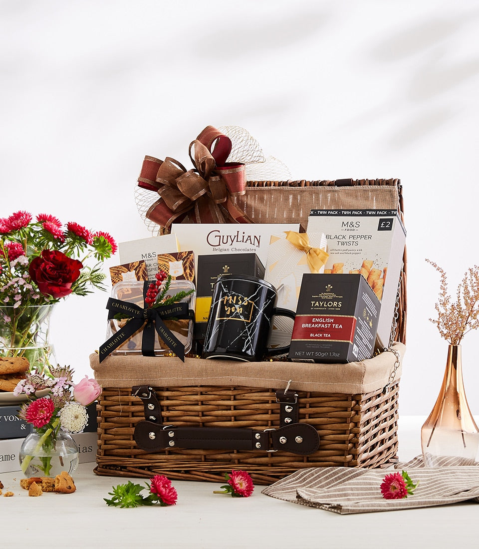 Woven wicker gift hamper with Belgian chocolates, English tea, gourmet treats, brown leather strap and gold ribbon bow