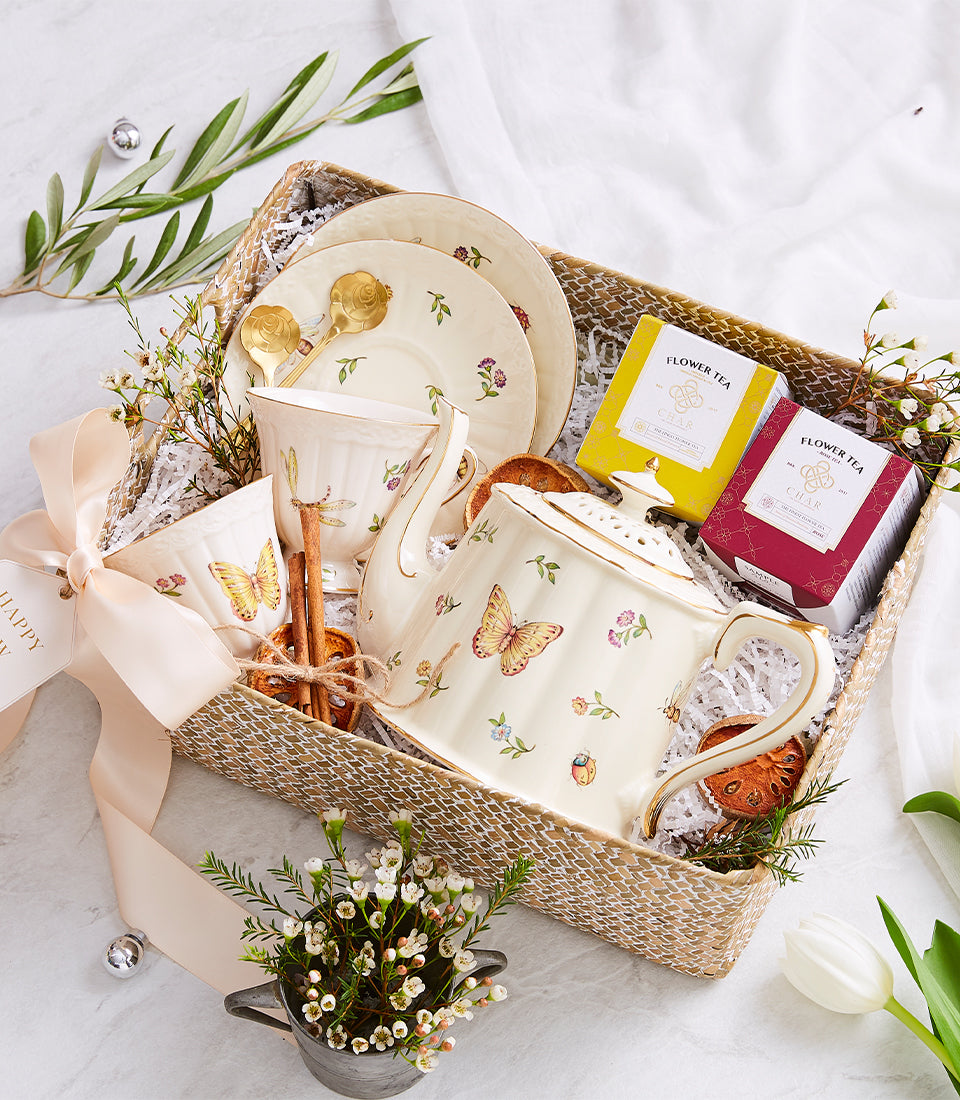 Basketeer premium hamper delivery Thailand: Teapot, cups, saucers, and flower tea in a woven gift box. Tied with a peach ribbon. A luxury gift basket Bangkok.