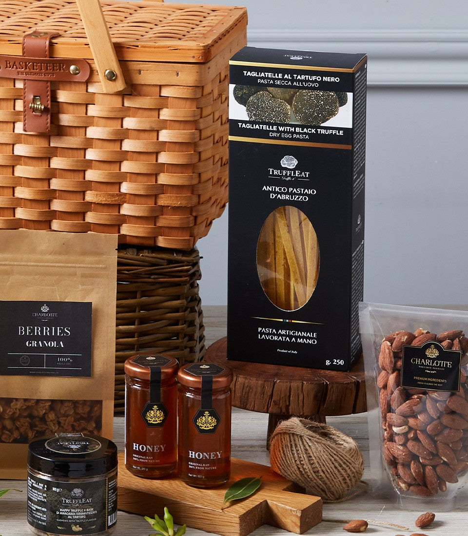 Luxury imported delicacies hamper with truffle pasta, gourmet spreads, honey, and artisan provisions in woven wicker basket