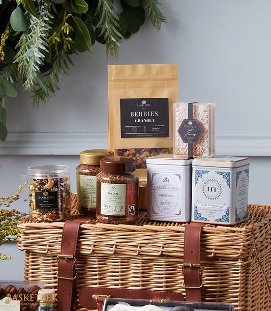 Luxury wicker hamper basket with gourmet coffee, tea, granola, nuts, and dried fruits in artisan packaging