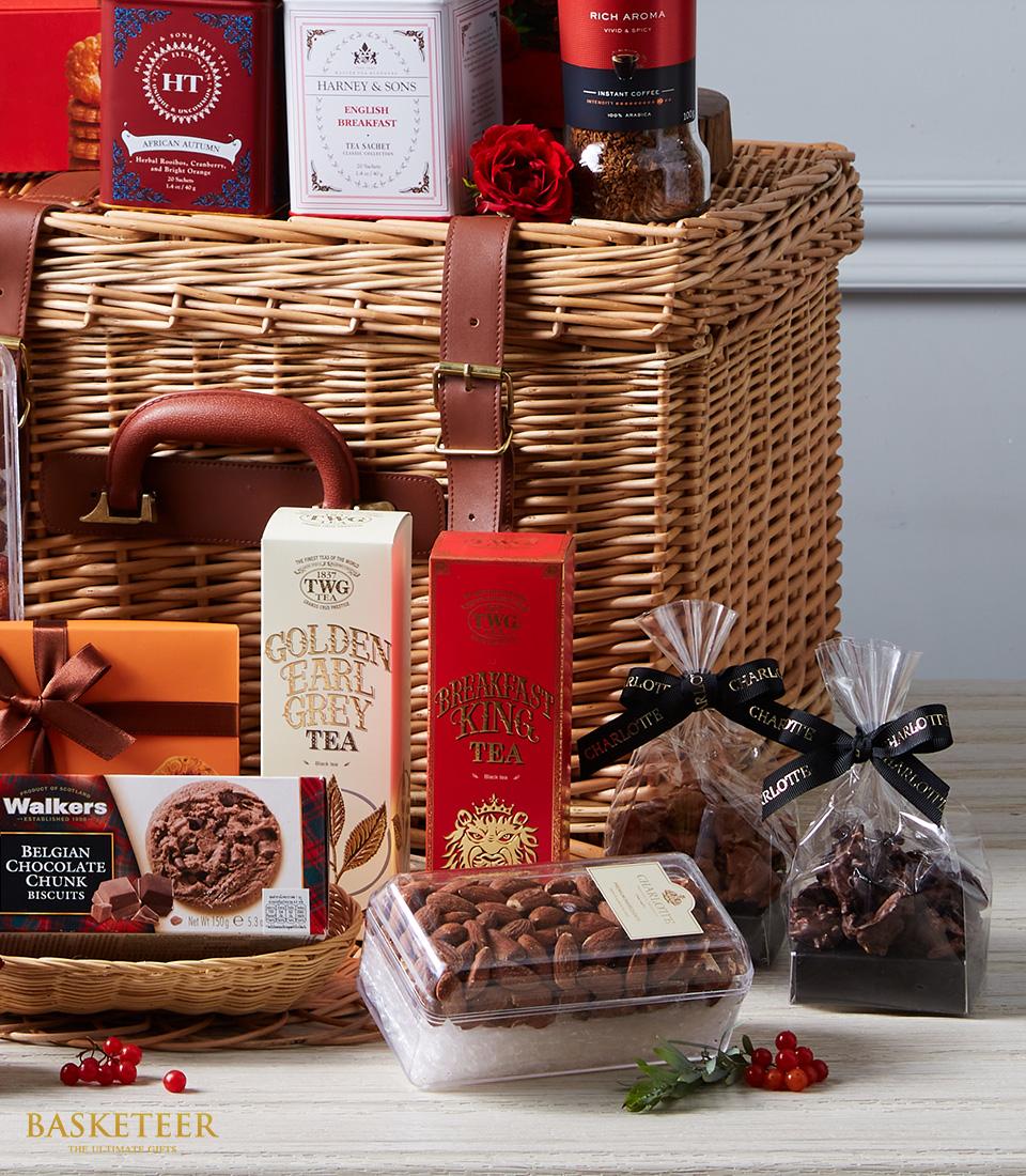 Luxury gift hamper with wicker basket, gourmet teas, imported chocolates, almonds, and red rose accent