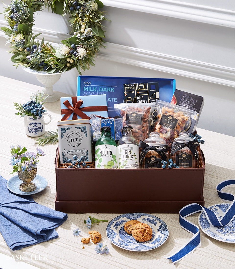 Luxury gourmet gift hamper with chocolates, tea, mocktails, nuts and artisan snacks in brown wooden box