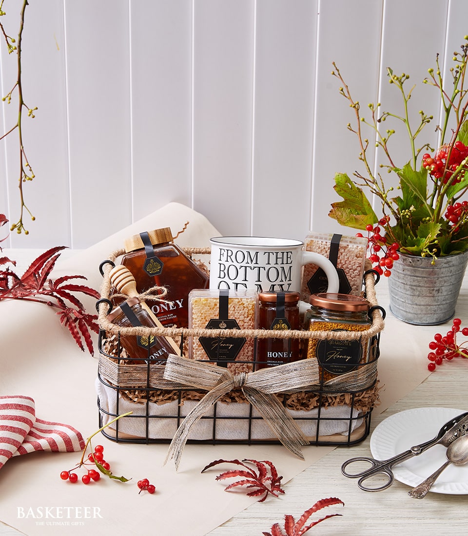 Luxury honey gift basket with artisan jars, honeycomb, wooden dipper, and ceramic mug for New Year gifting