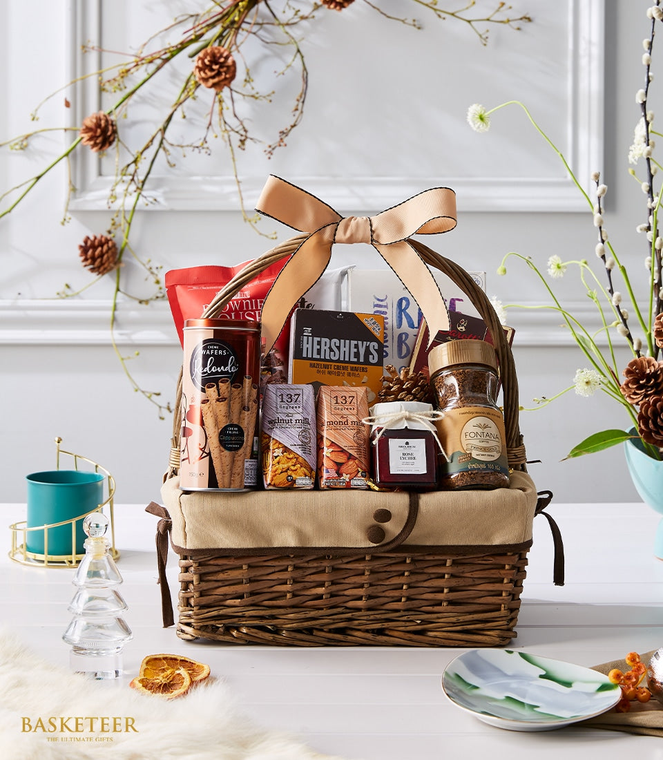 Woven wicker gift basket with peach ribbon, gourmet wafers, specialty coffee, plant-based milk, and jam for New Year gifting