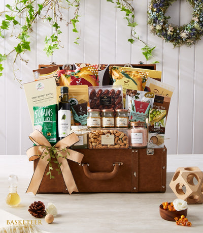 Luxury gourmet gift hamper in vintage leather suitcase with organic olive oil, rice cakes, dates, cashews, honey, and