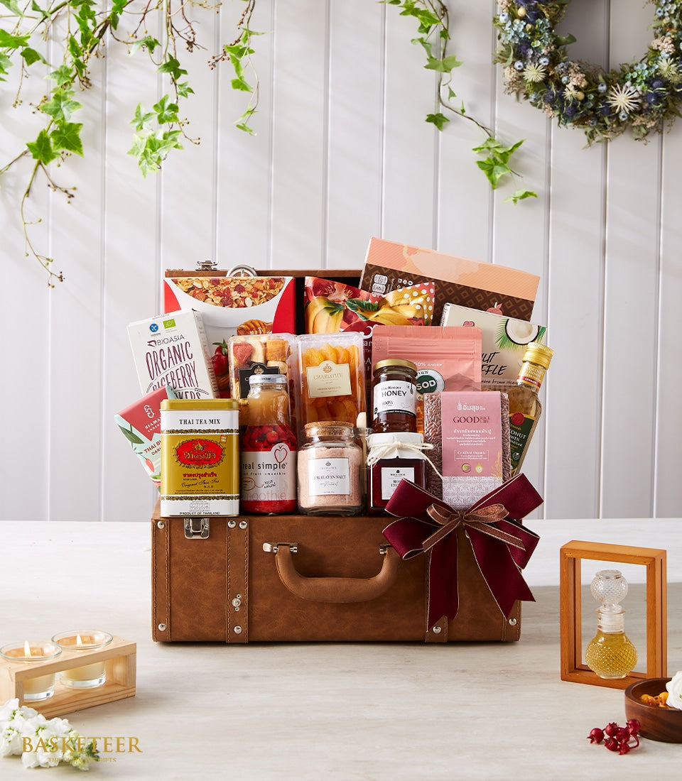 Luxury worldwide gourmet hamper in vintage brown suitcase with organic foods, honey, olive oil and red ribbon bow