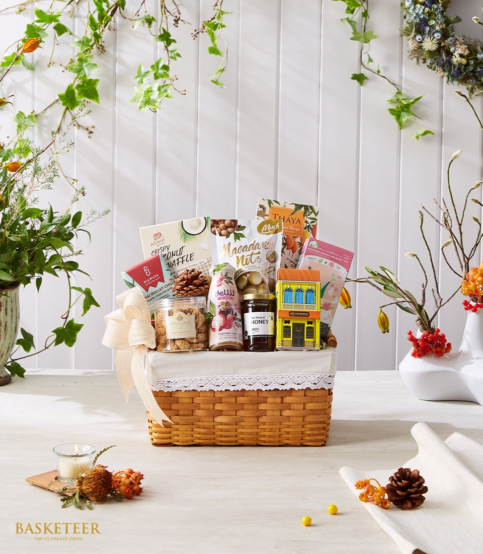 Woven gift basket with Thai treats including coconut waffle, macadamia nuts, dried mango, dark chocolate, honey, and artisan