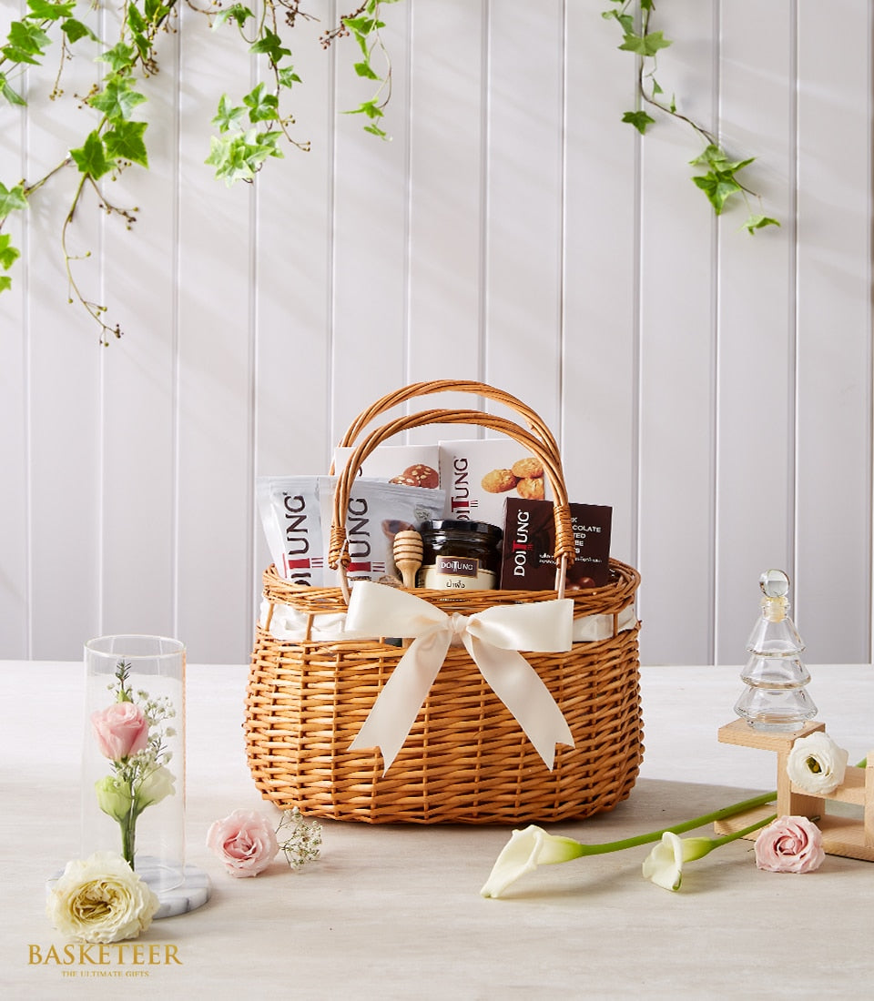 Doi Tung gourmet gift basket with honey, cookies, and premium artisan goods, styled with fresh roses and white flowers