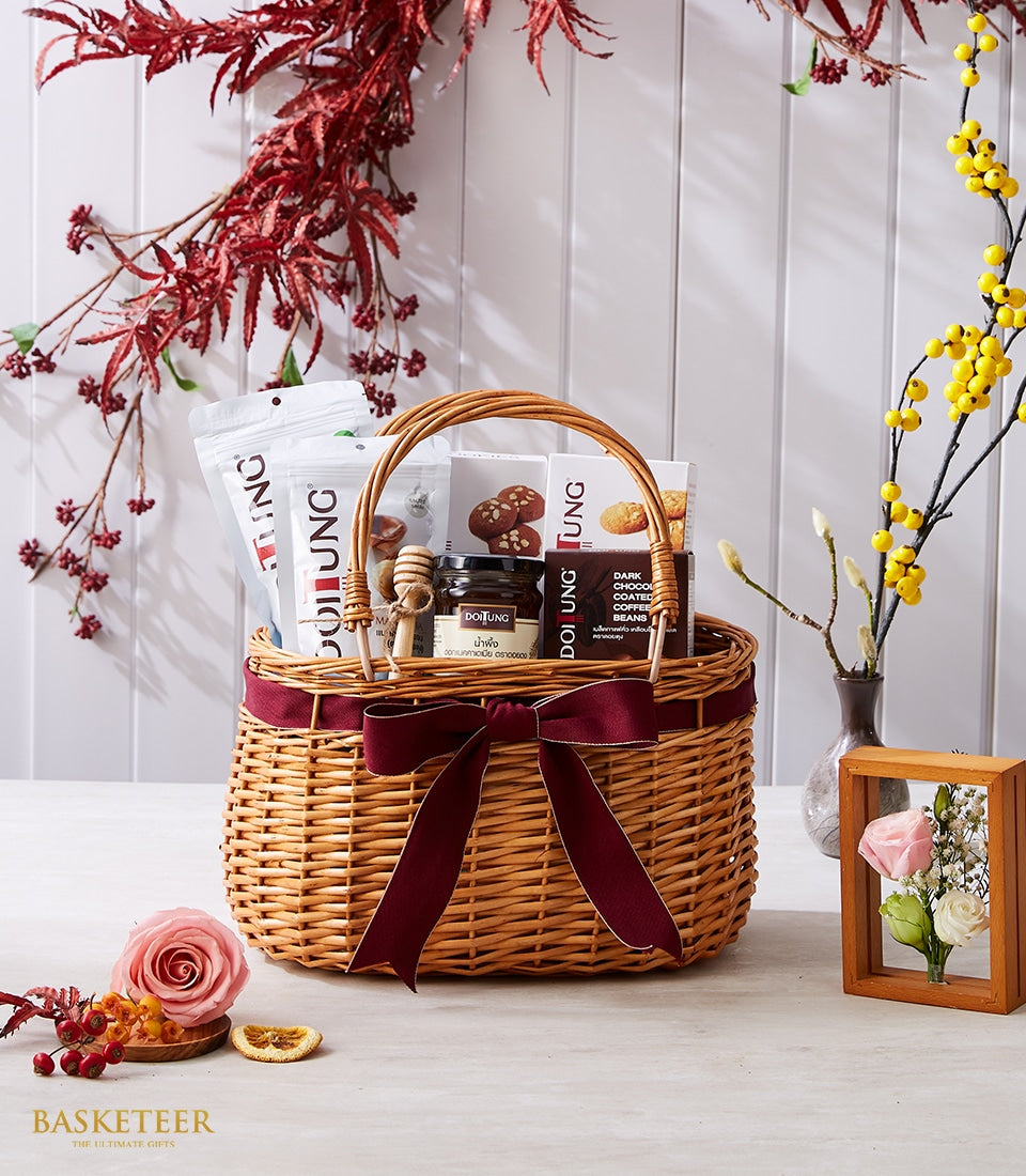 Premium wicker gift basket with dark red satin bow filled with Doi Tung gourmet treats, coffee, honey, and artisan goods