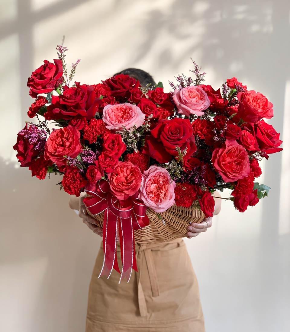Scarlet and blush roses in wicker basket with red satin bow, premium fresh flower arrangement for get well wishes