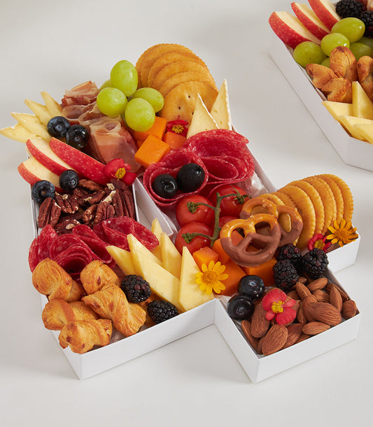 Number 1 charcuterie board with fresh fruits, artisan cheeses, cured meats, and edible flowers in white segmented tray